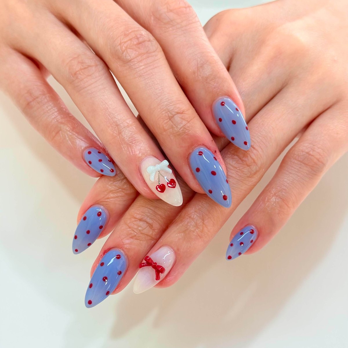 Blue and white nails decorated with cherries and sculpted bows