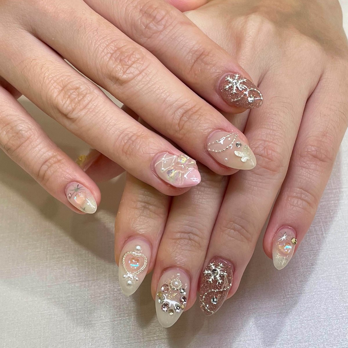 Sheer blush nails embellished with crystals and reflective details
